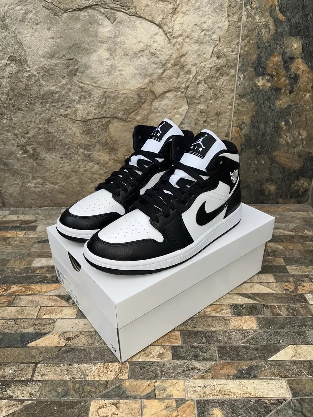Air Jordan 1 Mid Blanco / Negro. Par sobre la caja, vista de tres cuartos