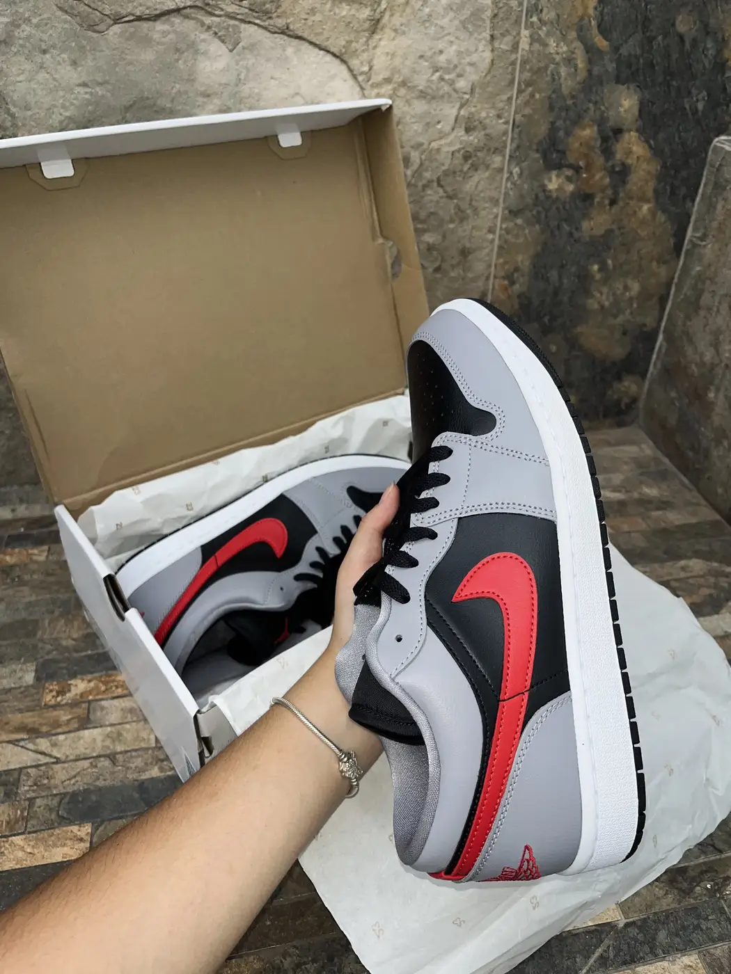 Air Jordan 1 Low Cement Fire Red. Lateral exterior sostenido en mano